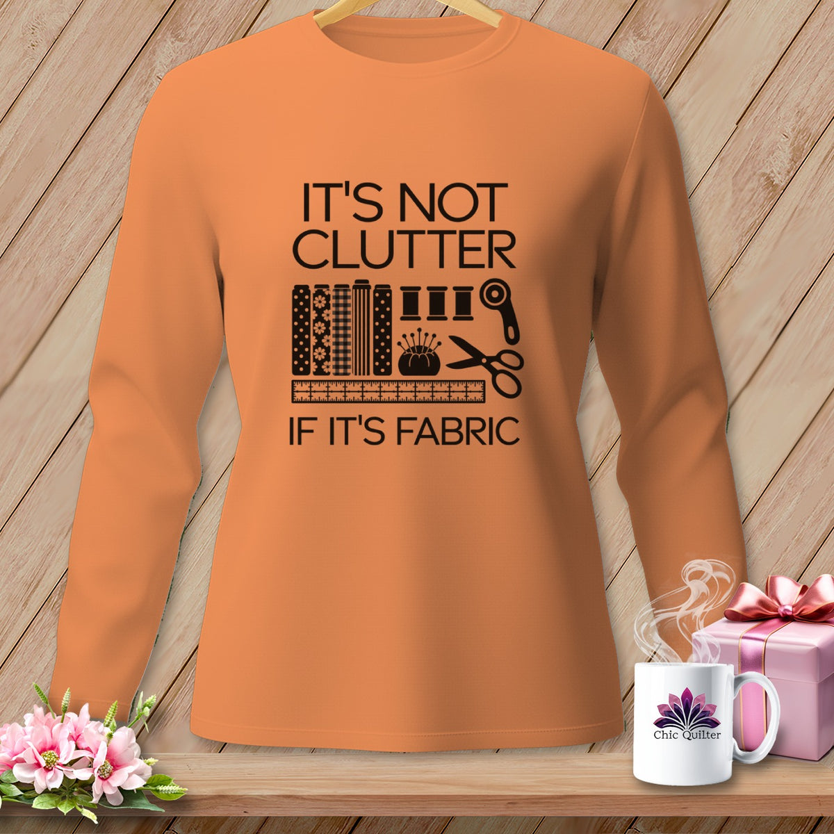 Orange long-sleeve shirt with "It's Not Clutter If It's Fabric" text and sewing graphics.