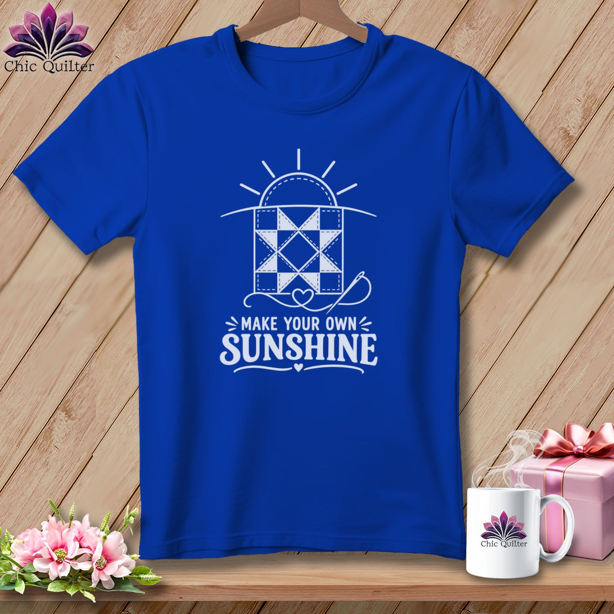 Blue t-shirt with a white graphic of a quilt and the text "Make Your Own Sunshine".