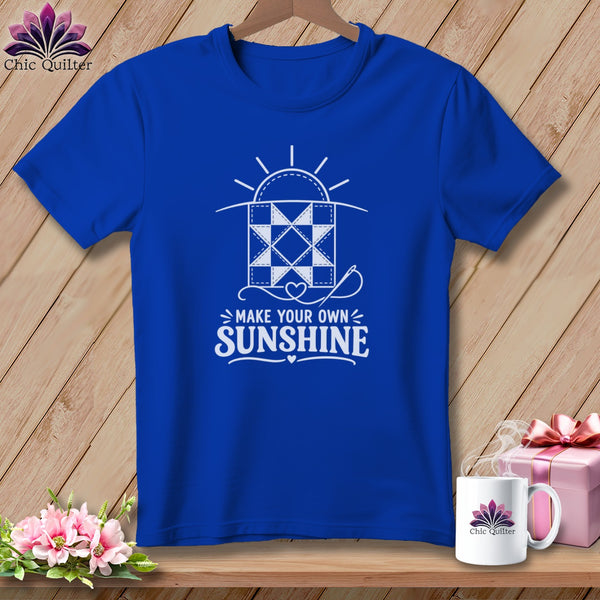 Blue t-shirt with a white graphic of a quilt and the text "Make Your Own Sunshine".