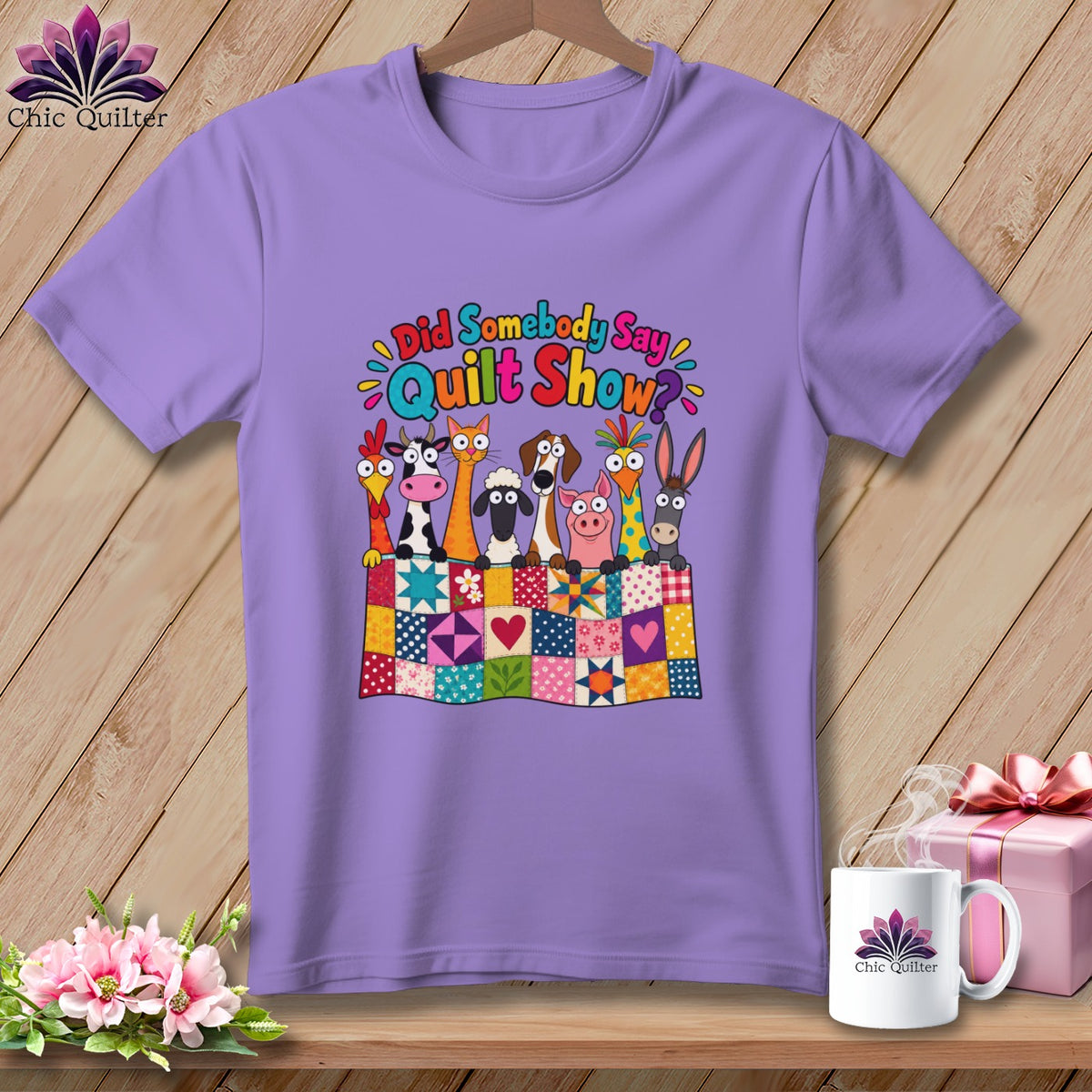 A light purple t-shirt features a colorful graphic of cartoon farm animals behind a patchwork quilt.
