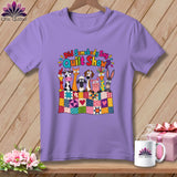 A light purple t-shirt features a colorful graphic of cartoon farm animals behind a patchwork quilt.