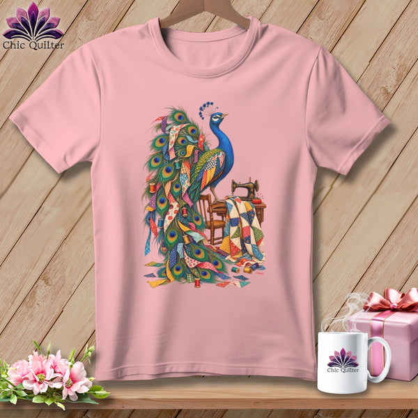 Pink t-shirt with a colorful peacock and sewing supplies graphic.