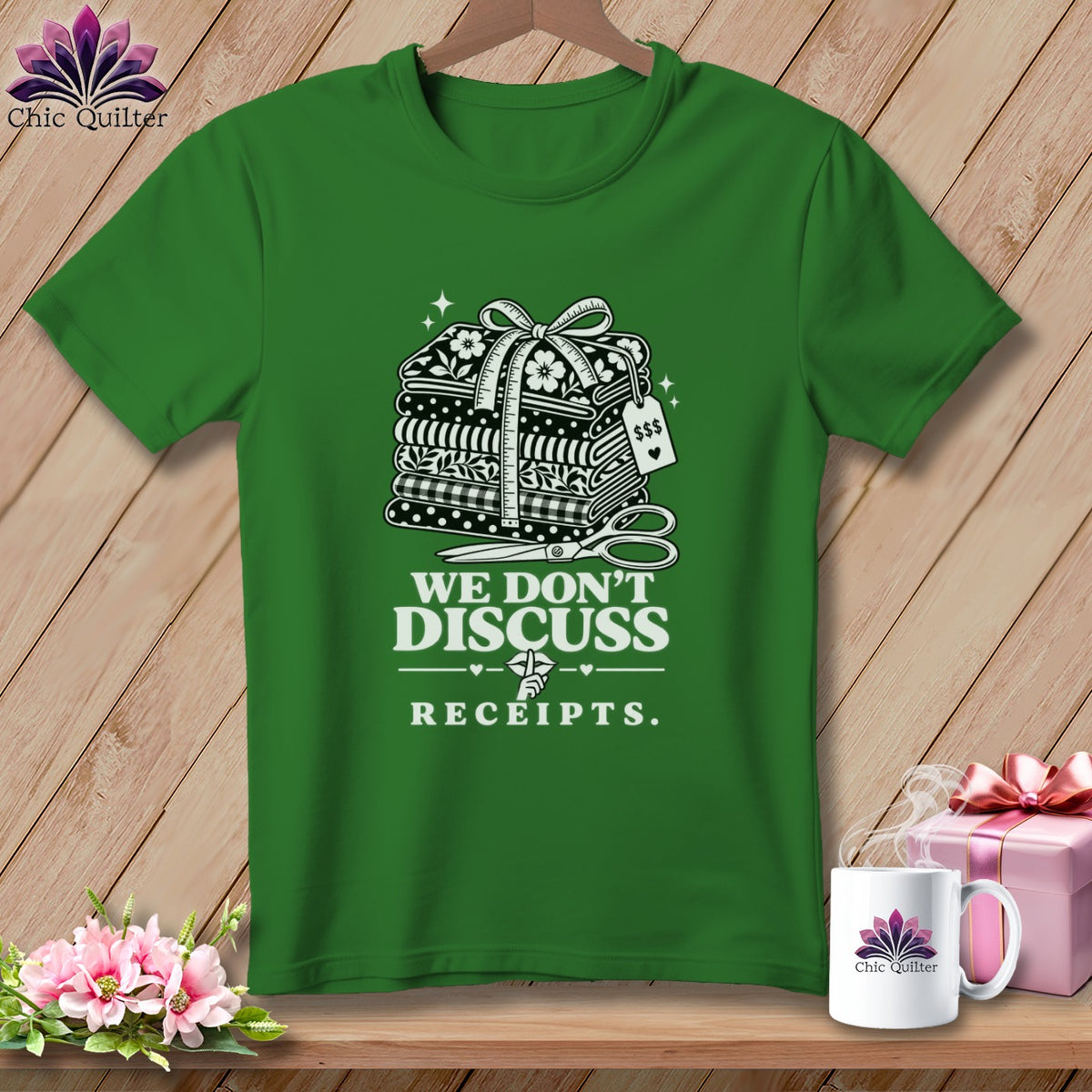 Green t-shirt with stacked fabric, scissors, and text "We Don't Discuss Receipts."