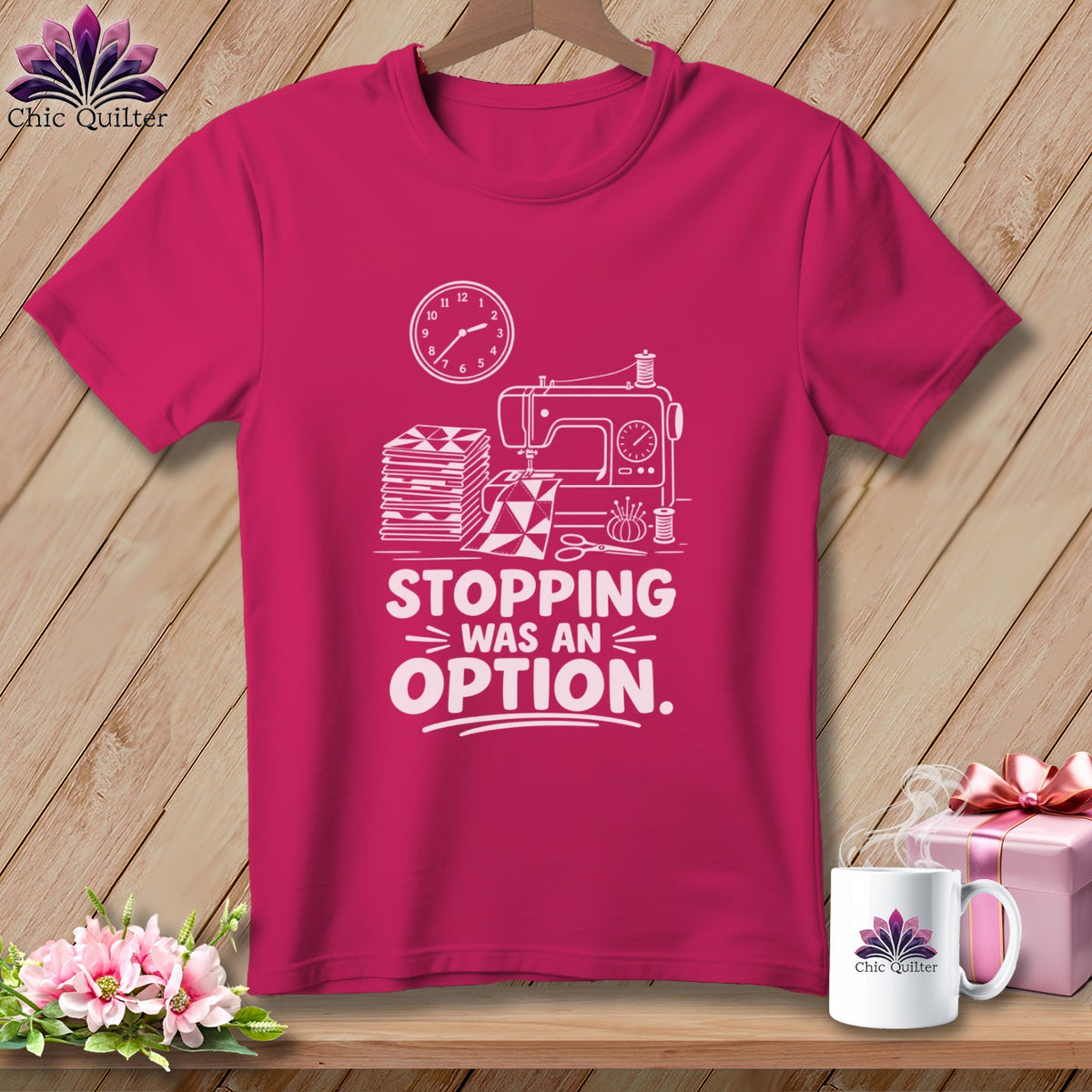 Pink t-shirt with sewing machine, fabric, clock, and "Stopping Was An Option" text.