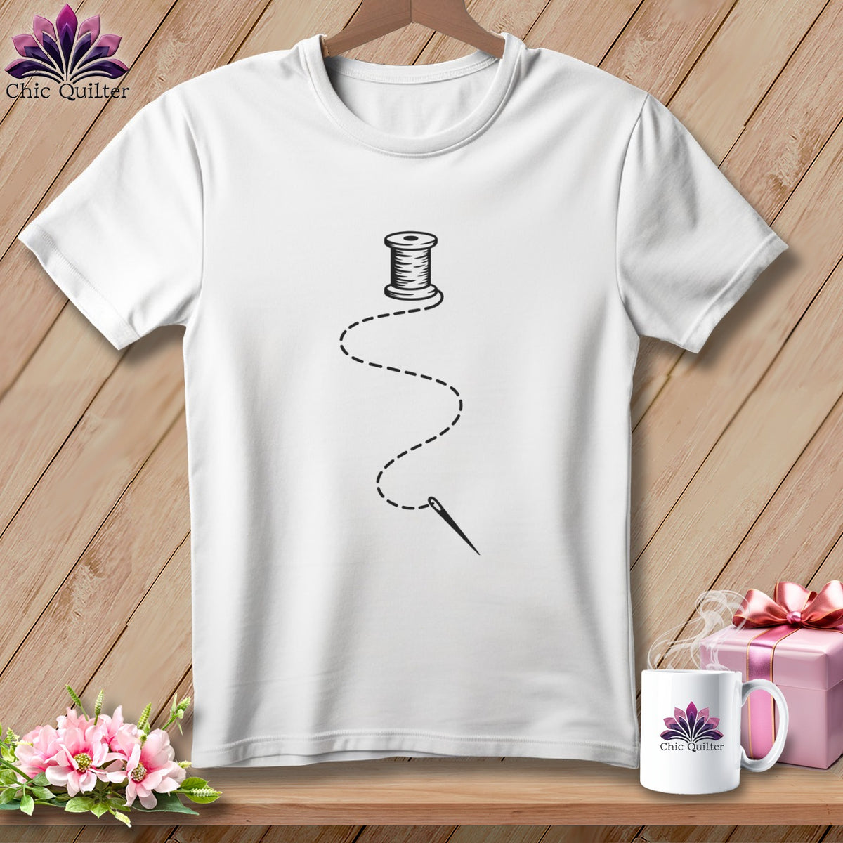 White t-shirt with a black spool of thread, needle, and dashed stitching design.