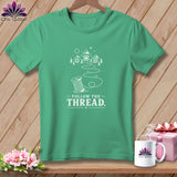 Green t-shirt with white graphic of a spool of thread and mountains, text reads 