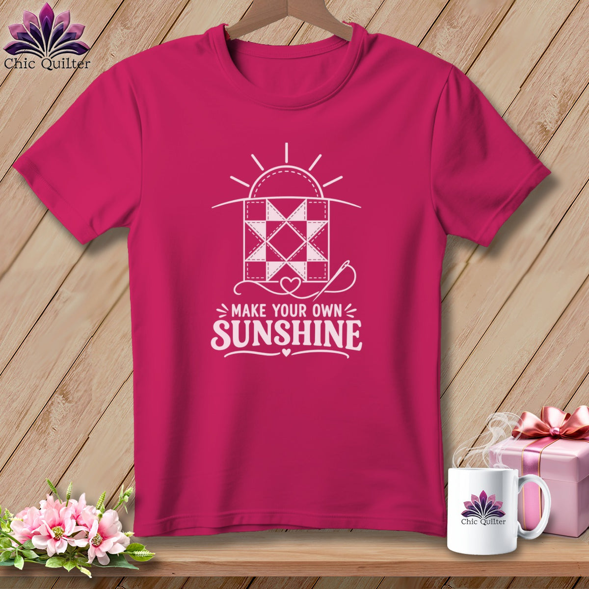 Pink t-shirt with white graphic of quilt block, sun, needle, and text "MAKE YOUR OWN SUNSHINE".