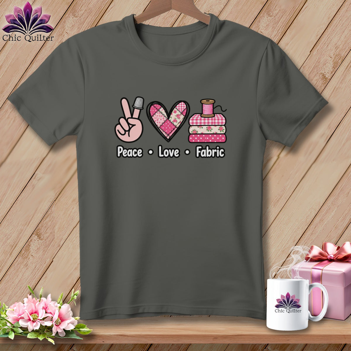 Dark grey t-shirt featuring a quilting graphic and the text Peace Love Fabric on a wooden background.