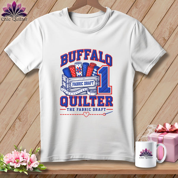 White t-shirt printed with Buffalo Quilter graphic featuring fabric rolls in a wooden crate.