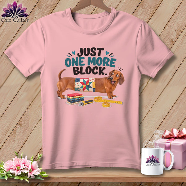 Pink t-shirt with dachshund wearing quilt block and text "JUST ONE MORE BLOCK".
