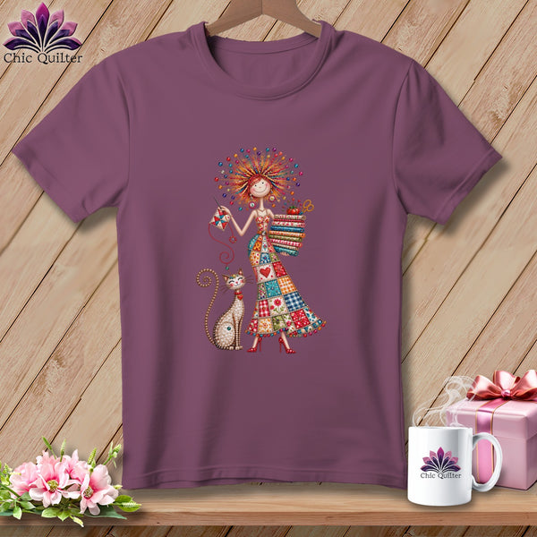 Mauve crewneck t-shirt featuring a whimsical illustration of a woman in a patchwork dress with a cat.