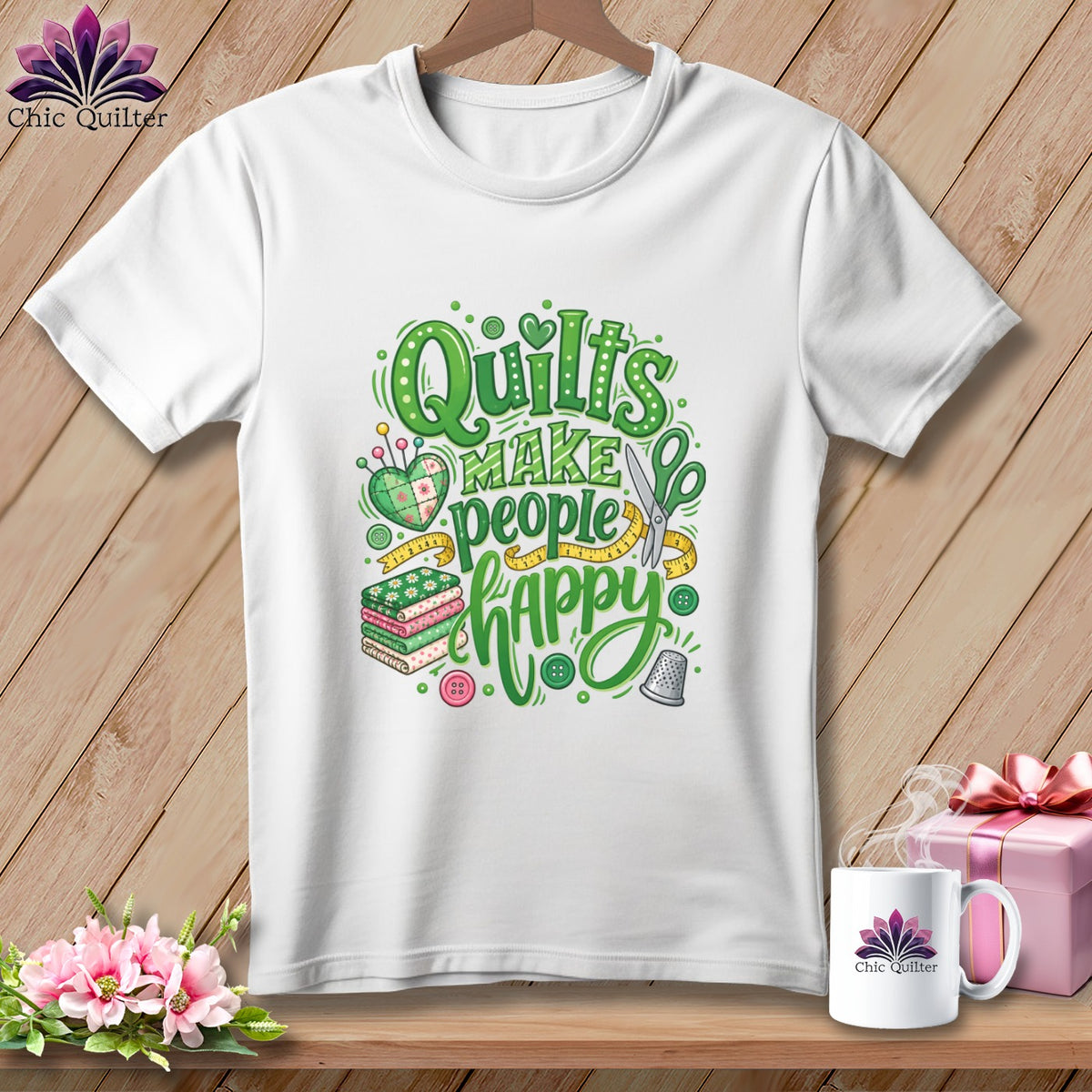 White t-shirt with a green graphic featuring sewing elements and the text Quilts Make People Happy.