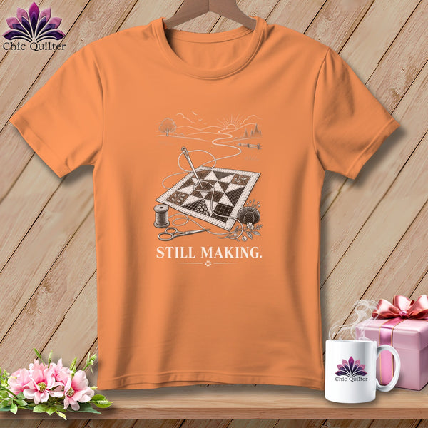 Orange t-shirt with quilting design, scissors, needle, and text "STILL MAKING."