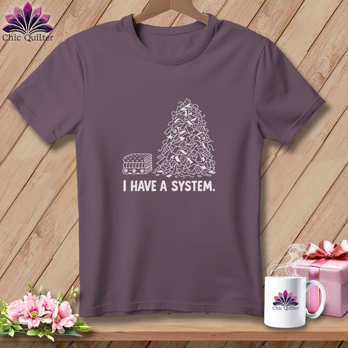 T-shirt with a pile of fabric scraps and folded fabric with text "I HAVE A SYSTEM."