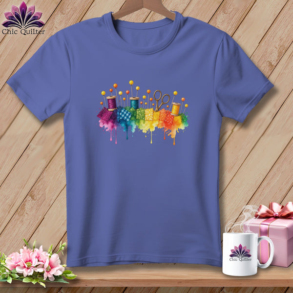 Purple t-shirt with colorful quilting supplies and rainbow watercolor splashes.
