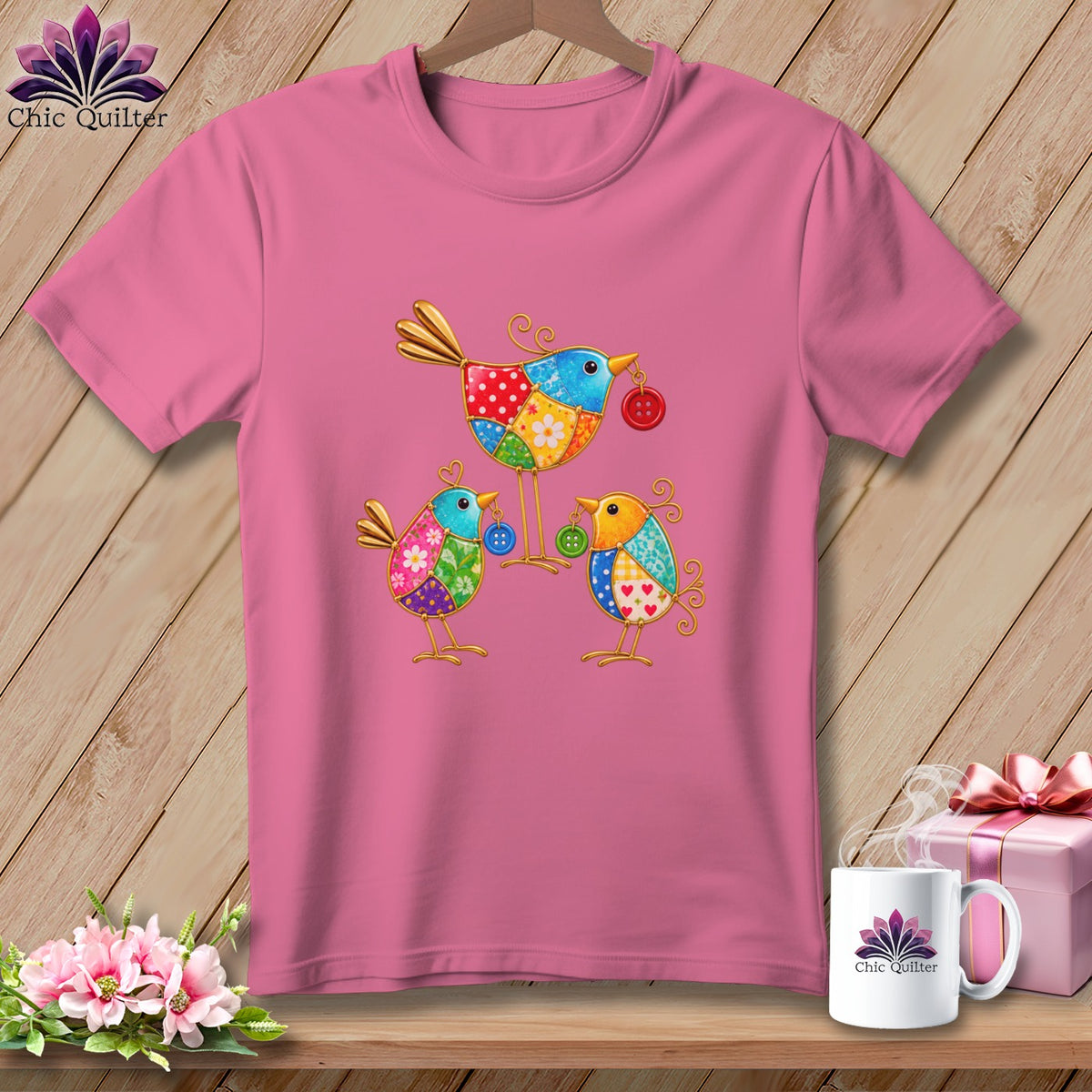 Pink t-shirt featuring a colorful patchwork design of three whimsical birds holding buttons.