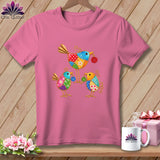Pink t-shirt featuring a colorful patchwork design of three whimsical birds holding buttons.