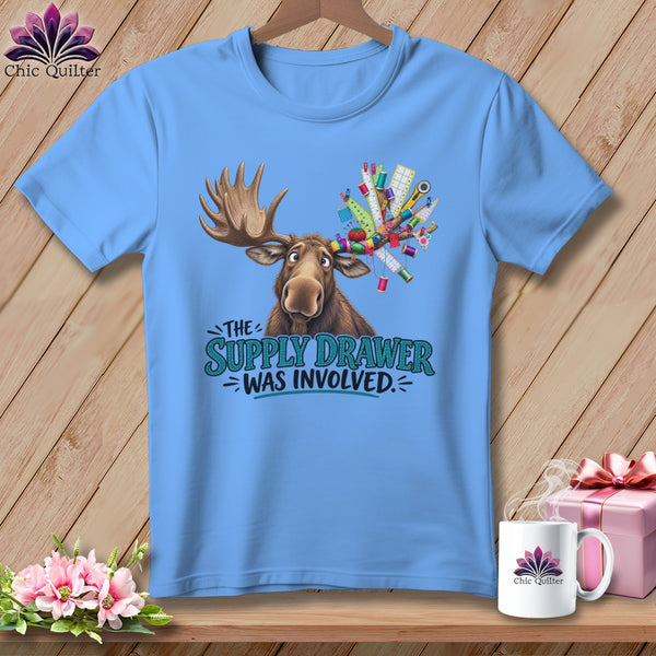 Light blue t-shirt with a cartoon moose holding sewing supplies and text.