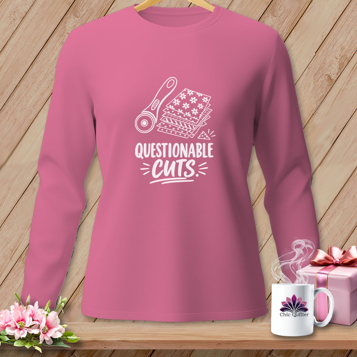 Pink long-sleeve shirt with "Questionable Cuts" graphic of rotary cutter and fabric.
