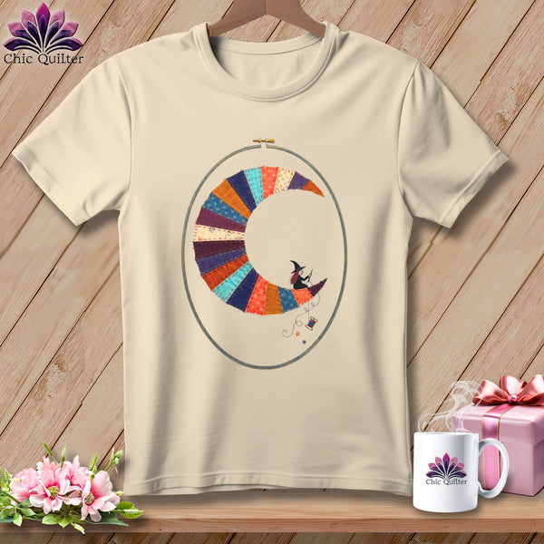 Cream t-shirt with embroidered crescent moon, witch, and sewing supplies.