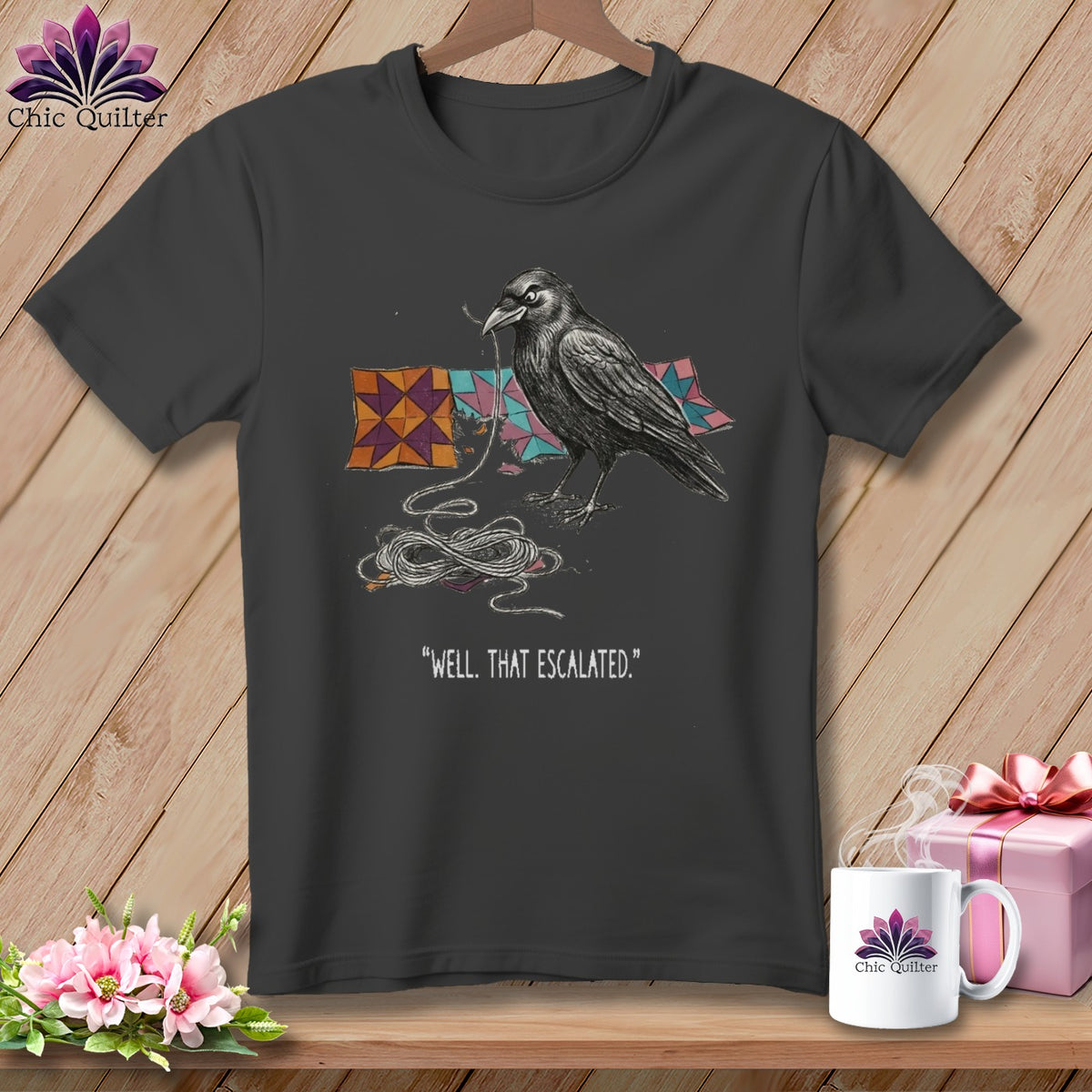 Dark t-shirt with a crow holding thread and quilt pieces, "Well, That Escalated." text.
