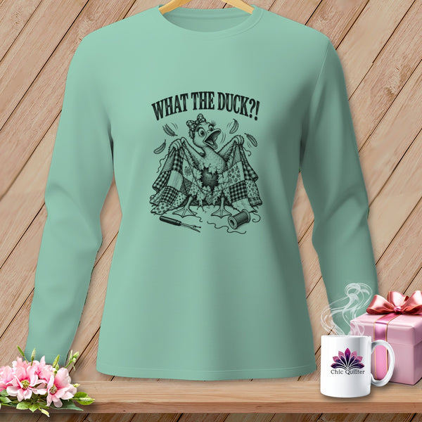 Light green long-sleeve t-shirt with a humorous black graphic of a duck holding a damaged quilt, featuring text reading WHAT THE DUCK?!