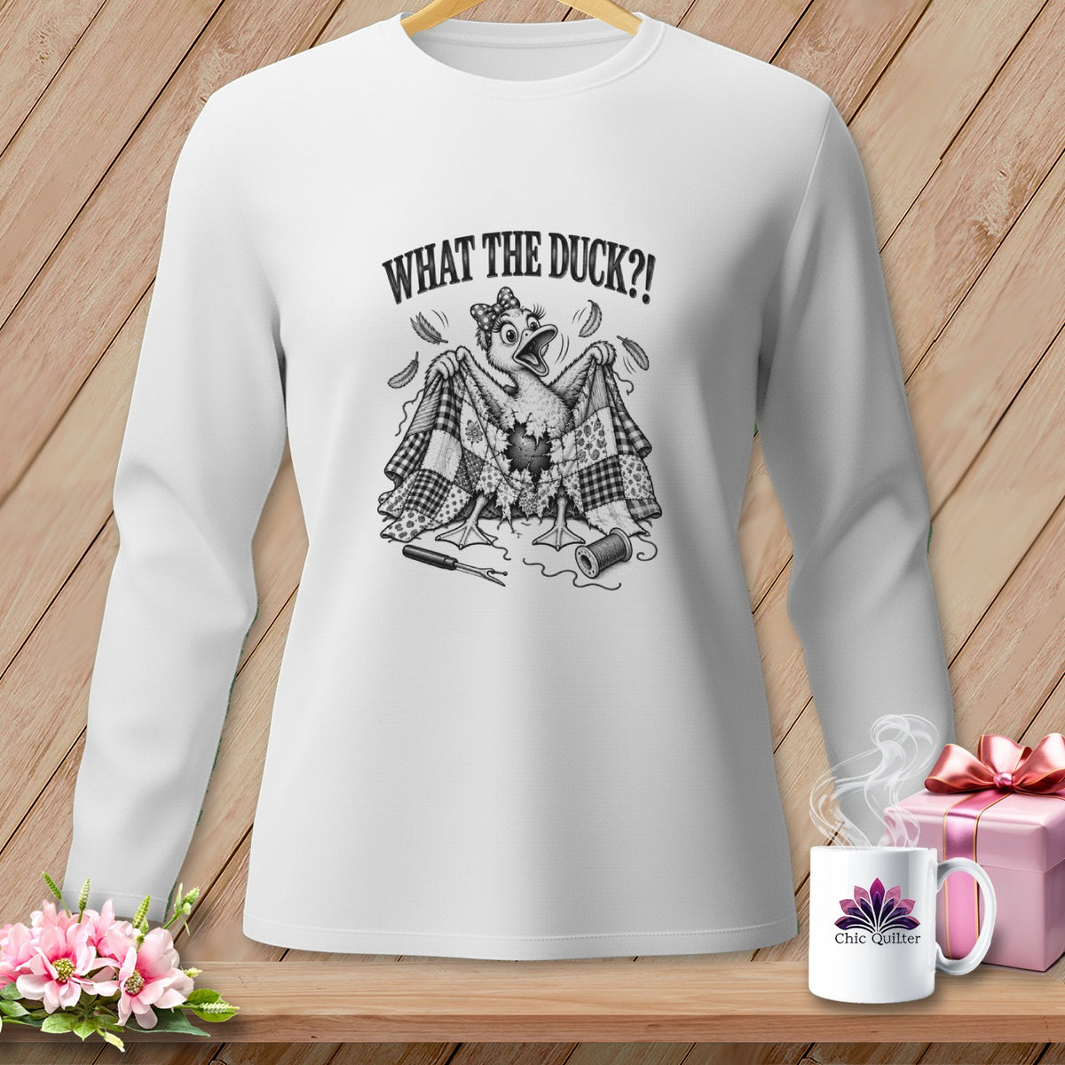 White long-sleeve t-shirt featuring a cartoon duck with a quilt, text that reads WHAT THE DUCK?!