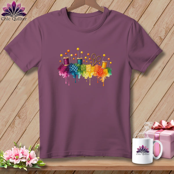 Plum t-shirt with watercolor sewing notions and fabric squares graphic.