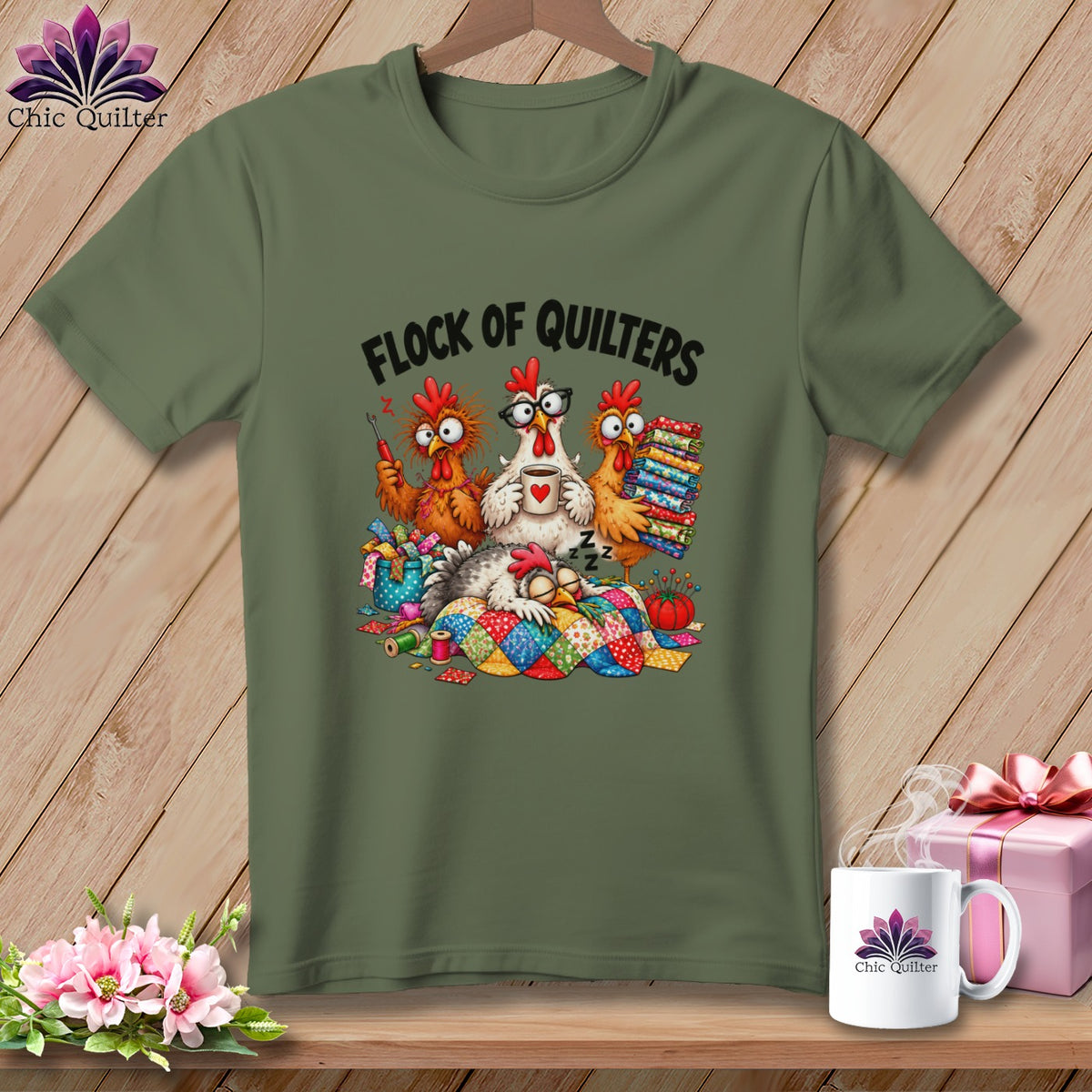 Olive green crewneck t-shirt featuring a cartoon illustration of cartoon chickens sewing, with the text Flock of Quilters.