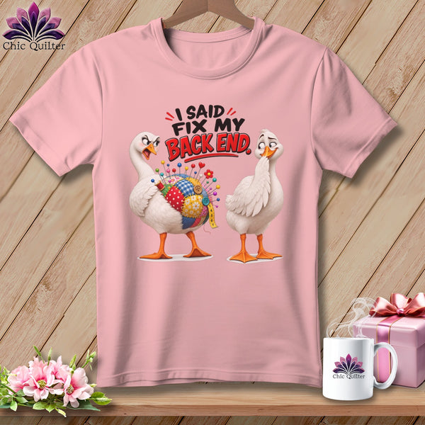 Pink t-shirt with two geese, one with a quilted patch and pins. Text reads "I SAID FIX MY BACK END."