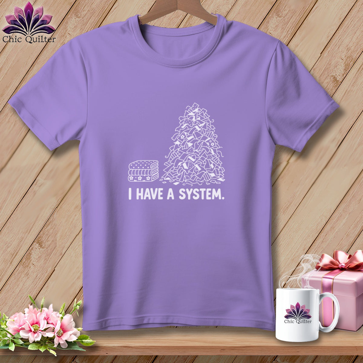 Purple t-shirt with white line drawing of fabric scraps and stacked fabric.