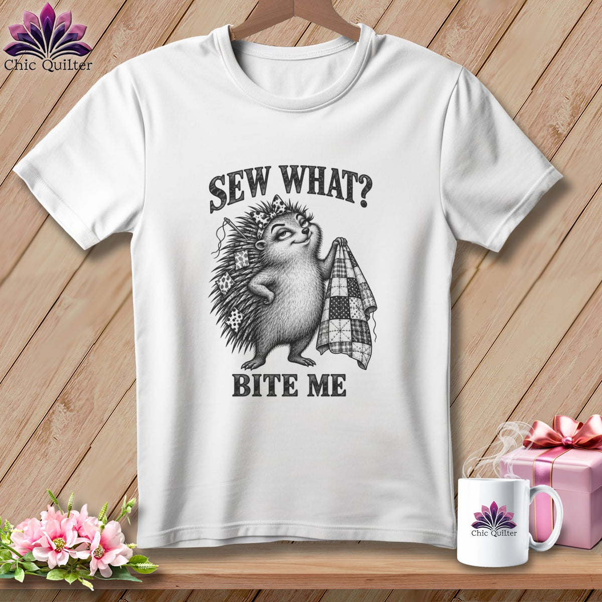 White t-shirt with a graphic of a hedgehog holding a quilt and the text Sew What? Bite Me.