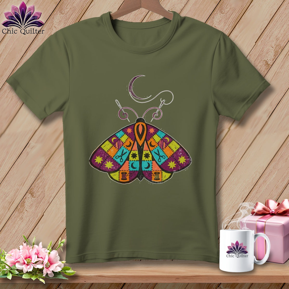 Olive green t-shirt with a colorful patchwork moth graphic and sewing needle.