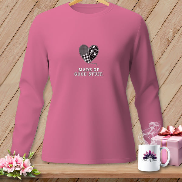 Pink long-sleeve shirt with a patchwork heart graphic and text "MADE OF GOOD STUFF".