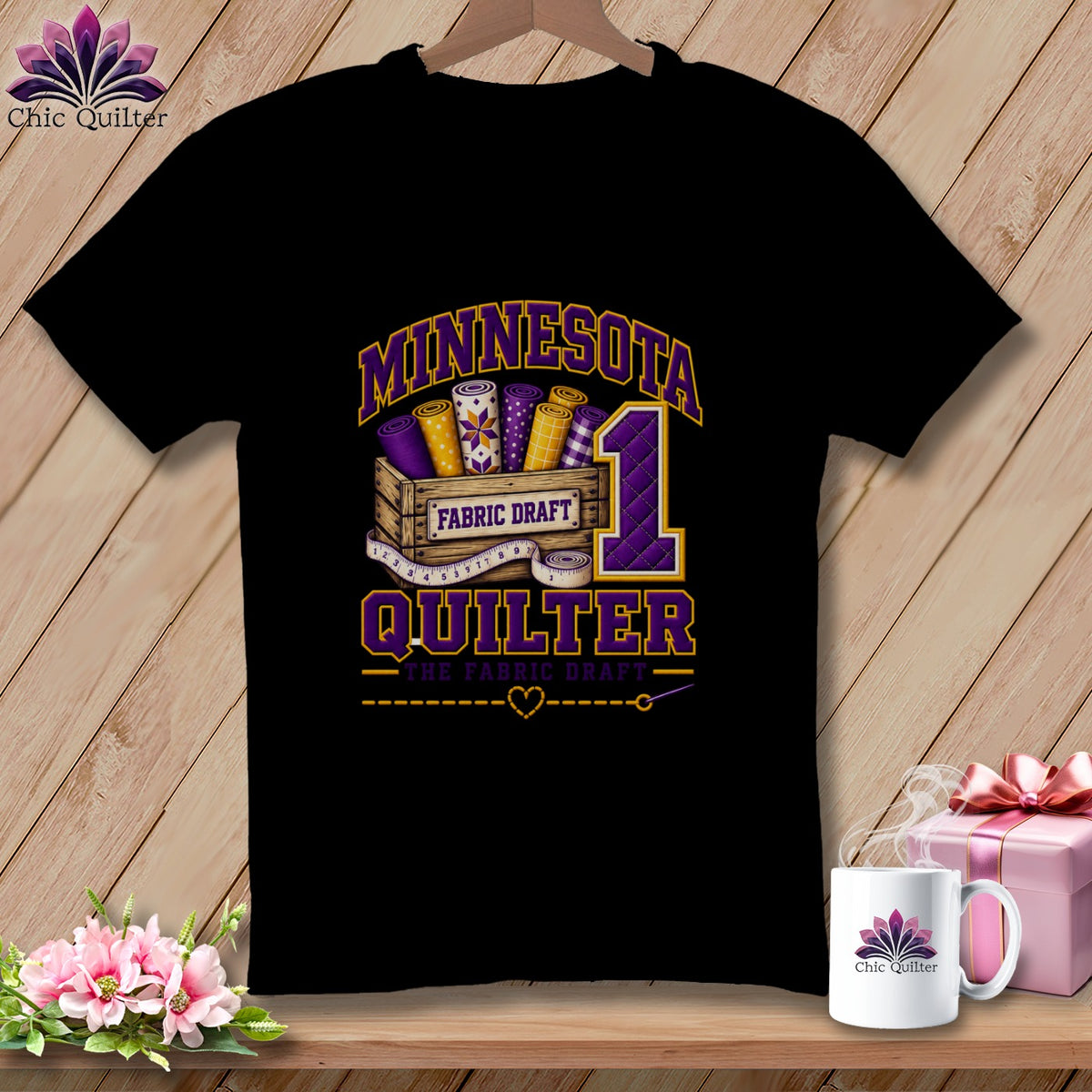 Black t-shirt featuring a Minnesota Quilter graphic with fabric bolts, a crate, and a large number one.