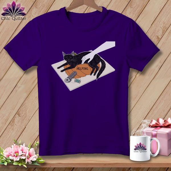Purple t-shirt with graphic of black cat, hand, and sewing tools with word "HELPING".