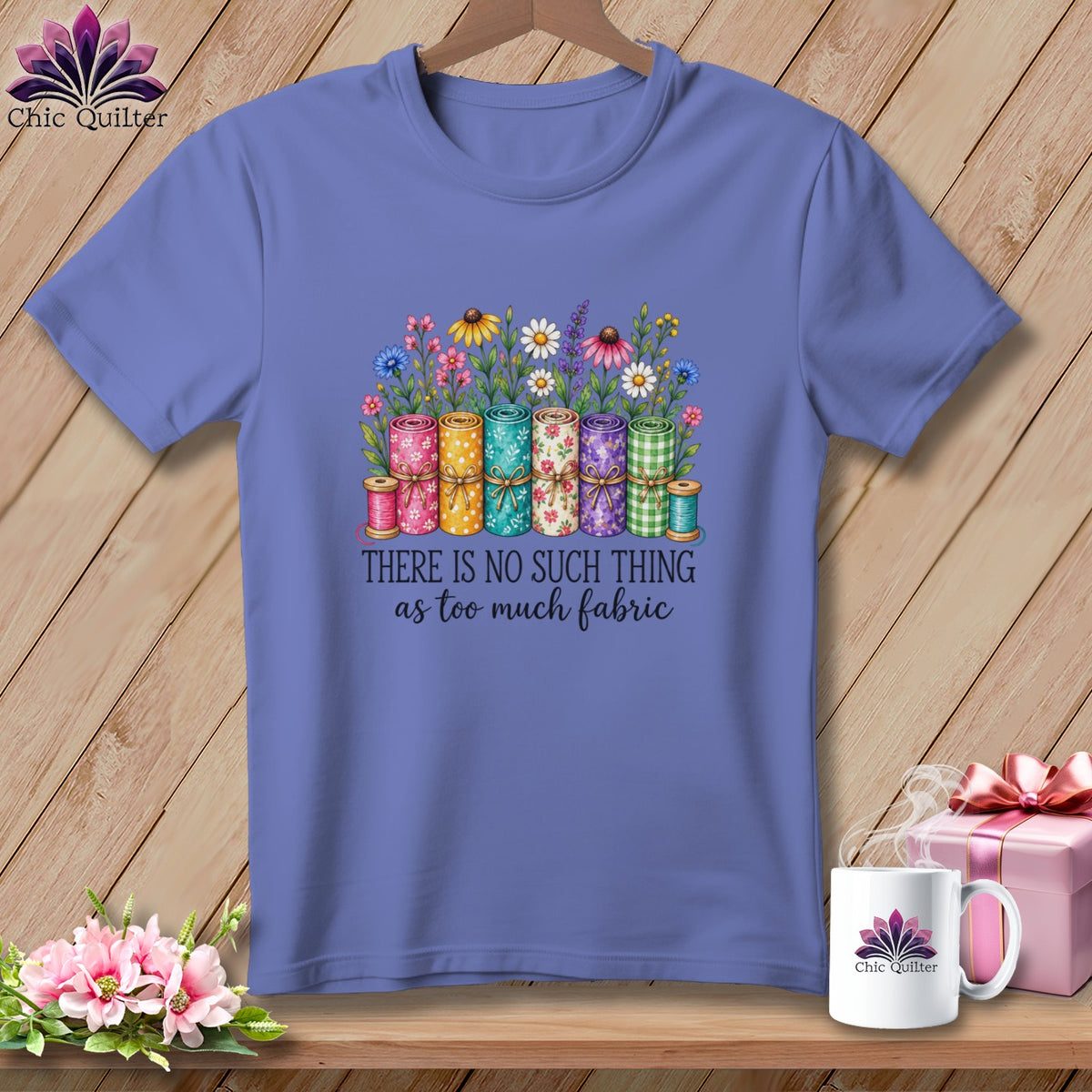 Blue t-shirt featuring a graphic of fabric rolls, flowers, and the text There Is No Such Thing As Too Much Fabric.