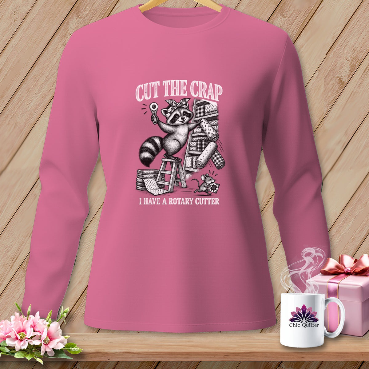 Long-sleeved pink shirt with raccoon holding rotary cutter, and text "Cut the Crap I Have a Rotary Cutter".