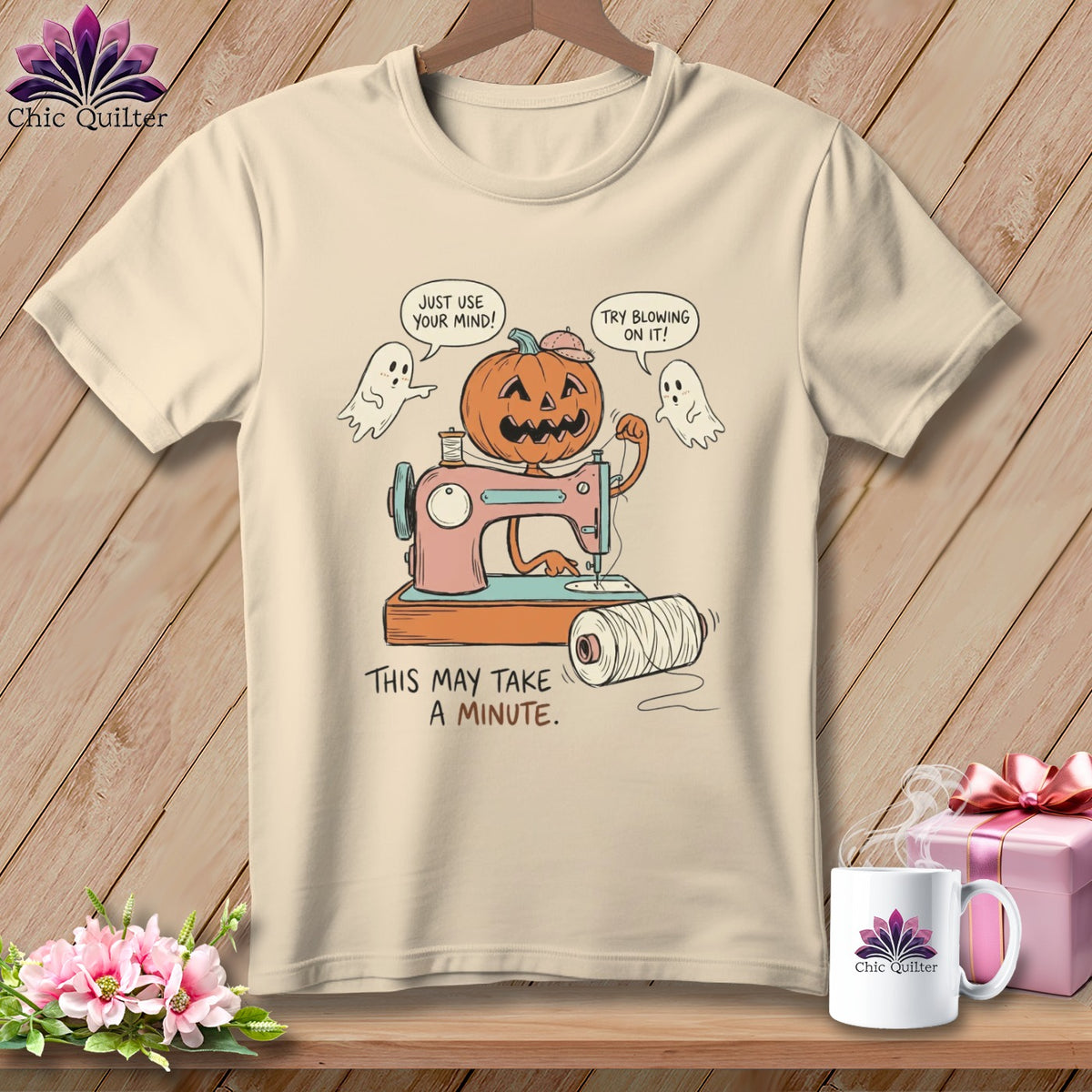 T-shirt with a cartoon pumpkin using a sewing machine, two ghosts, and text.