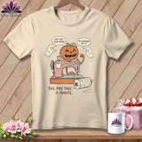 T-shirt with a cartoon pumpkin using a sewing machine, two ghosts, and text.