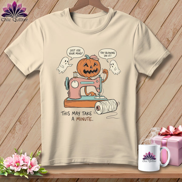 T-shirt with a cartoon pumpkin using a sewing machine, two ghosts, and text.