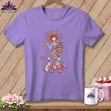 Purple t-shirt featuring an illustration of a woman in a patchwork dress holding a cat, on a wooden background.