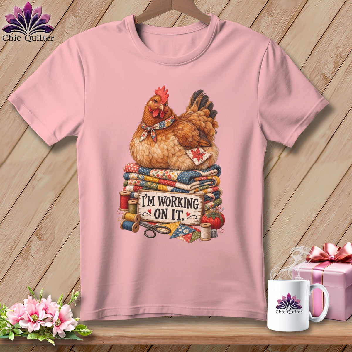 Pink t-shirt with a chicken on quilts and the text "I'M WORKING ON IT."