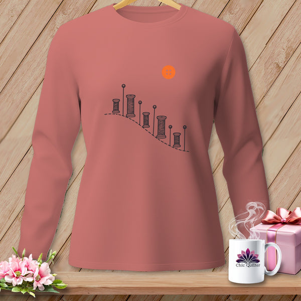 Long-sleeve rose shirt with spools of thread graphic and orange button.