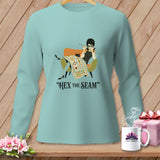 Light blue long-sleeve shirt with graphic of woman, cat, and quilt, and text 