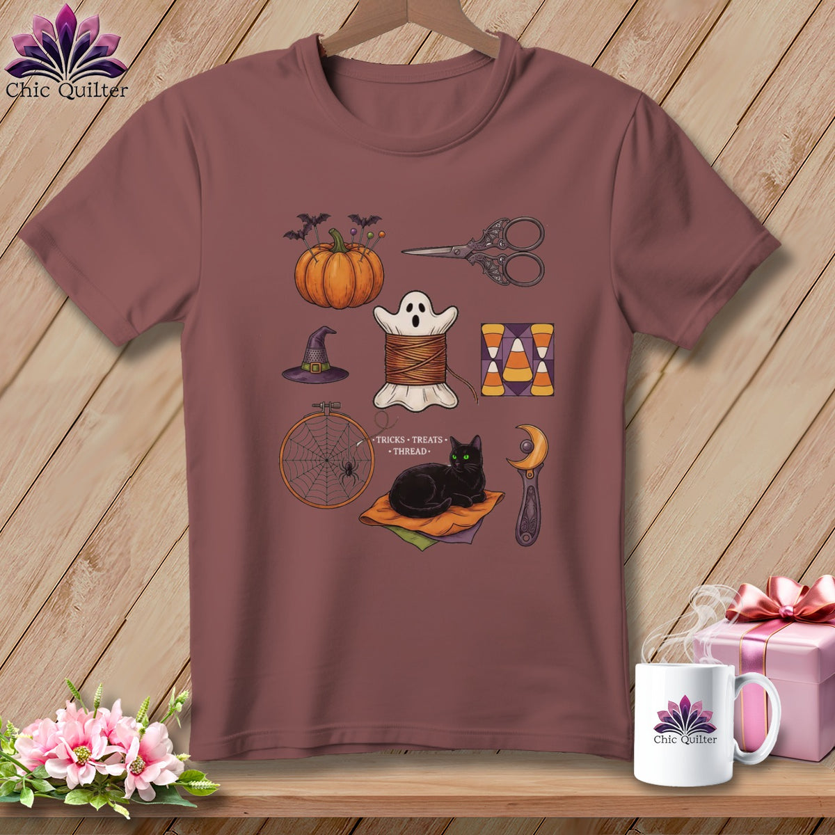 T-shirt with Halloween-themed sewing illustrations: pumpkin, ghost, scissors, cat, and spiderweb.