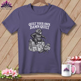 Purple t-shirt featuring a graphic of a bear and raccoon quilting with the text Quilt Your Own Damn Quilt.