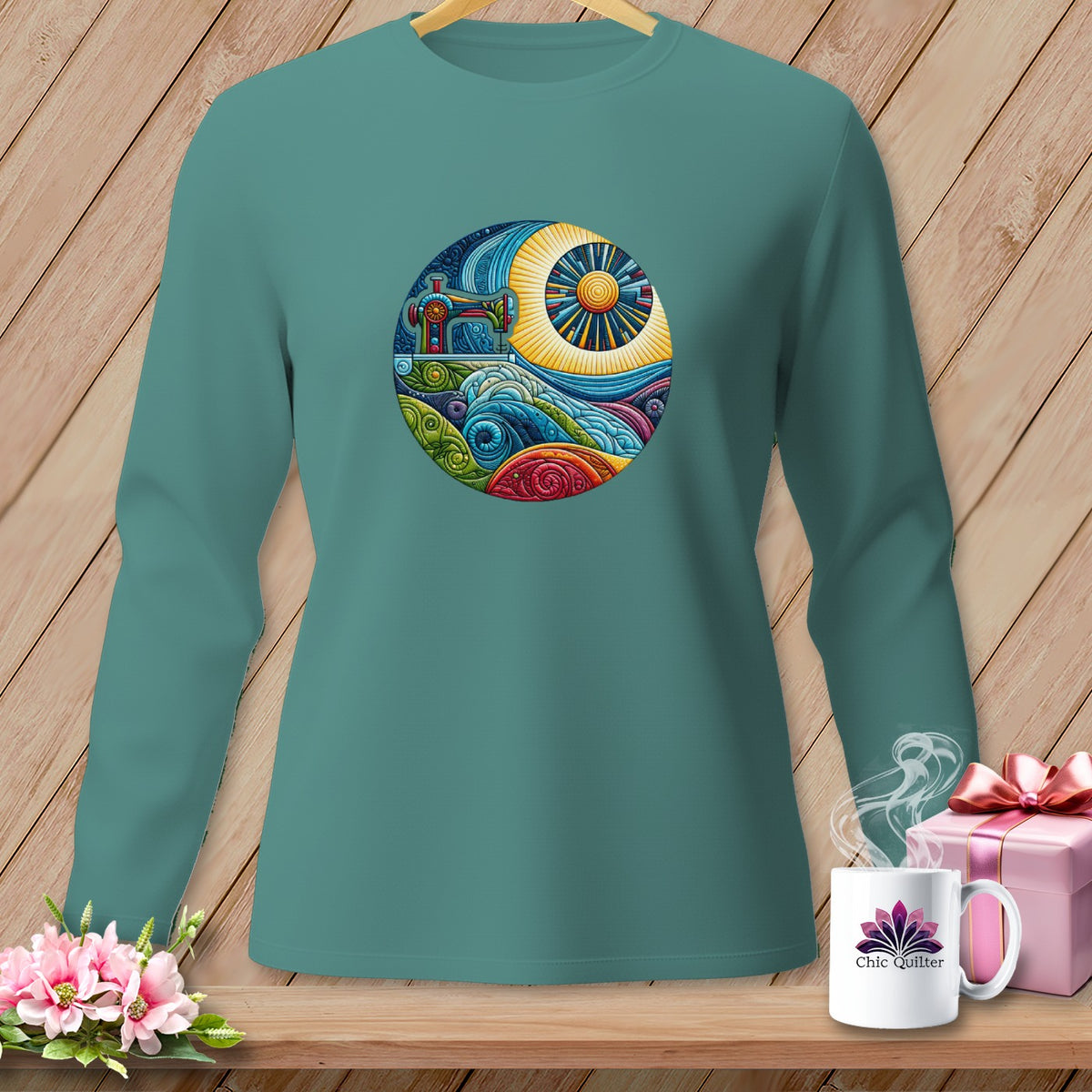 Teal long-sleeve shirt with circular graphic of sewing machine and colorful landscape.