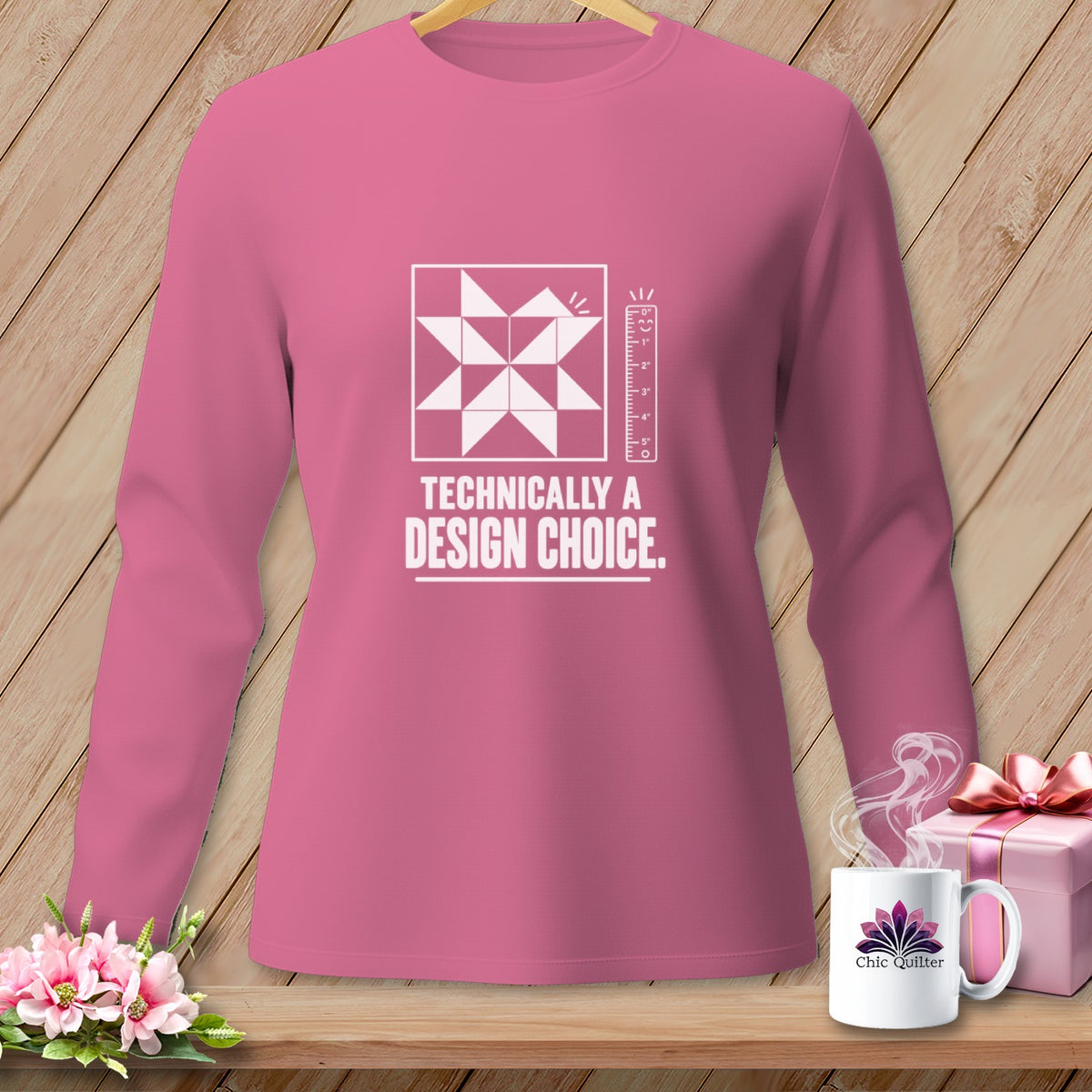 Pink long-sleeved shirt with a quilt block and "Technically a Design Choice" text.