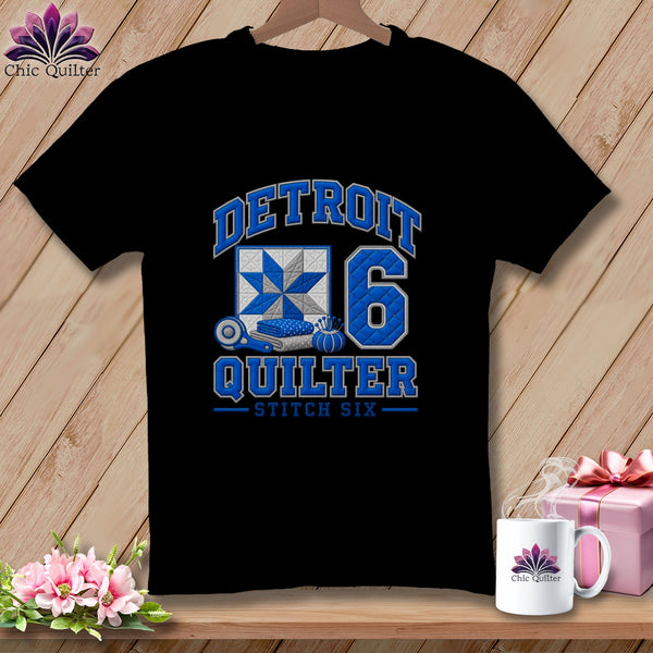 A black t-shirt features blue text reading DETROIT QUILTER STITCH SIX, a quilt block, and the number six.